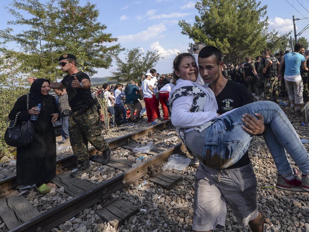 Dos inmigrantes cruzan el cordón de fuerzas especiales para llegar a Grecia en Gevgelija, Macedonia.