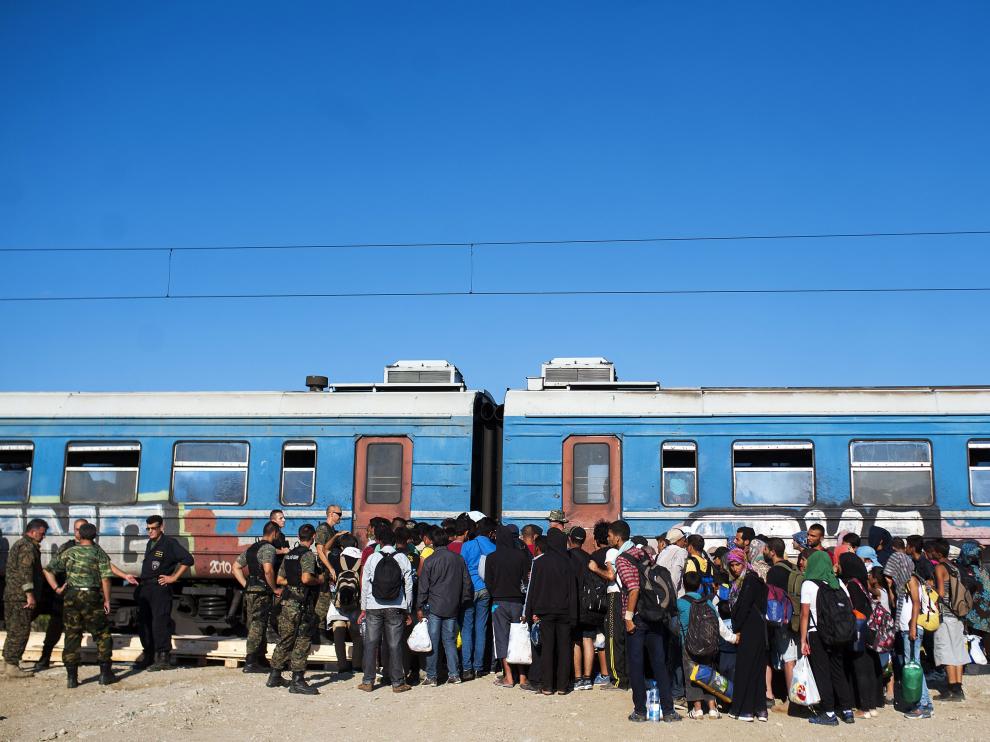 Varios inmigrantes esperan a subirse a un tren para viajar a Serbia.
