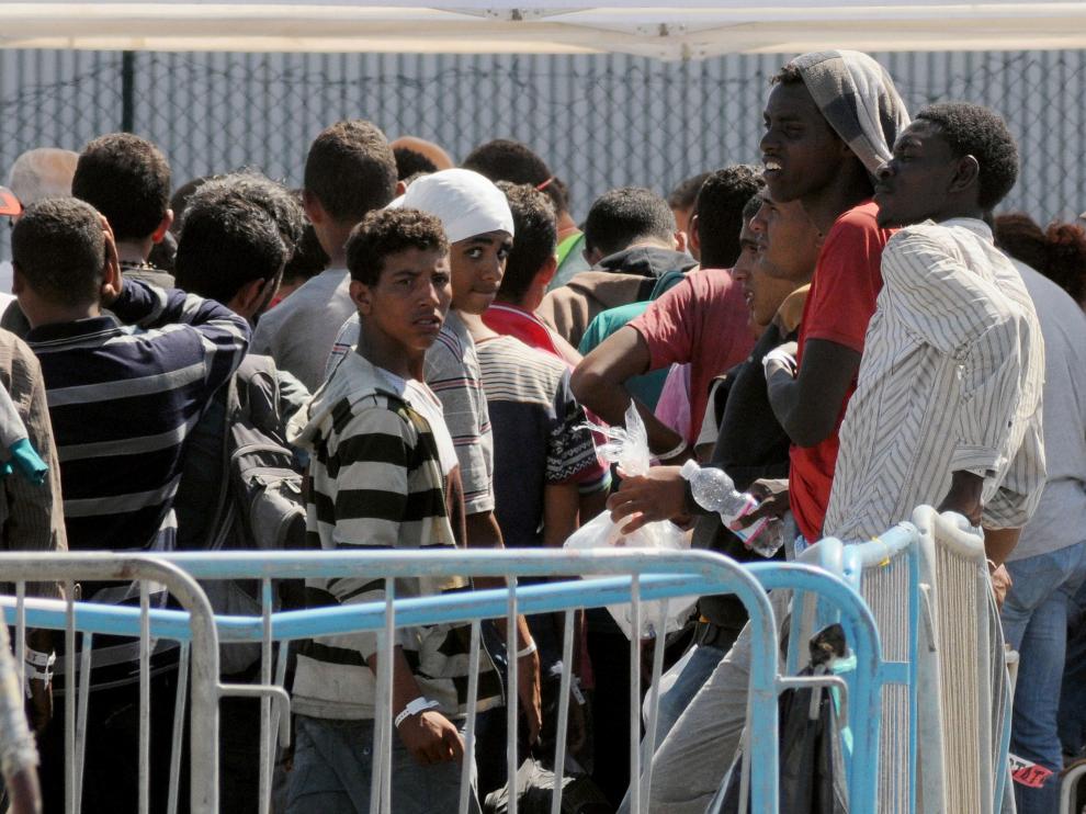 Los inmigrantes esperan tras llegar a la costa italiana.