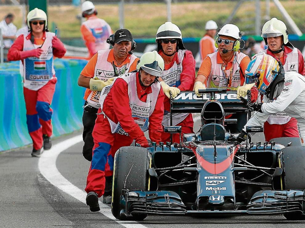 Alonso empuja su McLaren hacia los boxes ayudado por unos comisarios, ayer en la Q2.