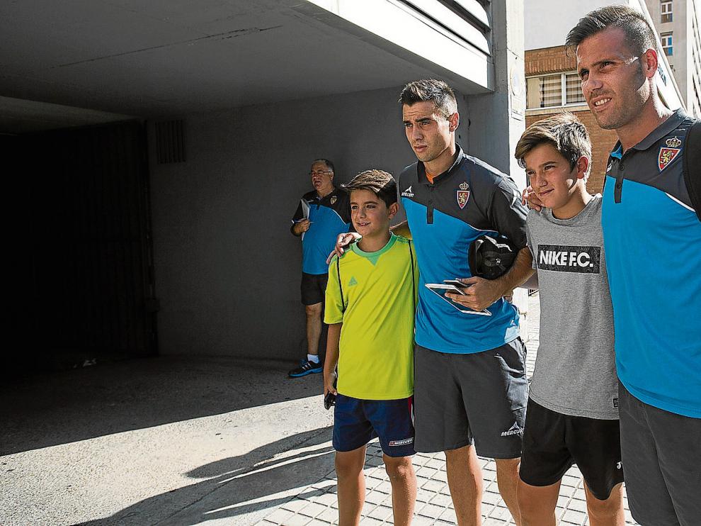 Jaime y Ortuño posan con dos jóvenes aficionados antes de la partida del equipo zaragocista rumbo a Miranda de Ebro.