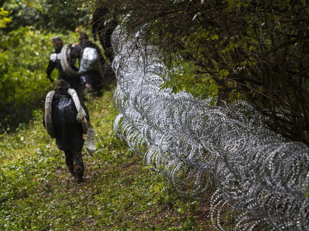Varios soldados húngaros levantan una alambrada en la frontera con Croacia.