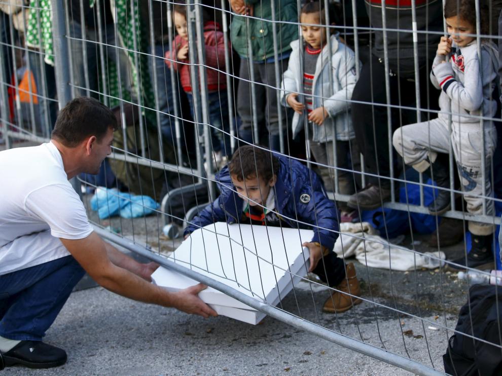 Un camarero entrega una pizza a un grupo de niños en la frontera de Eslovenia.
