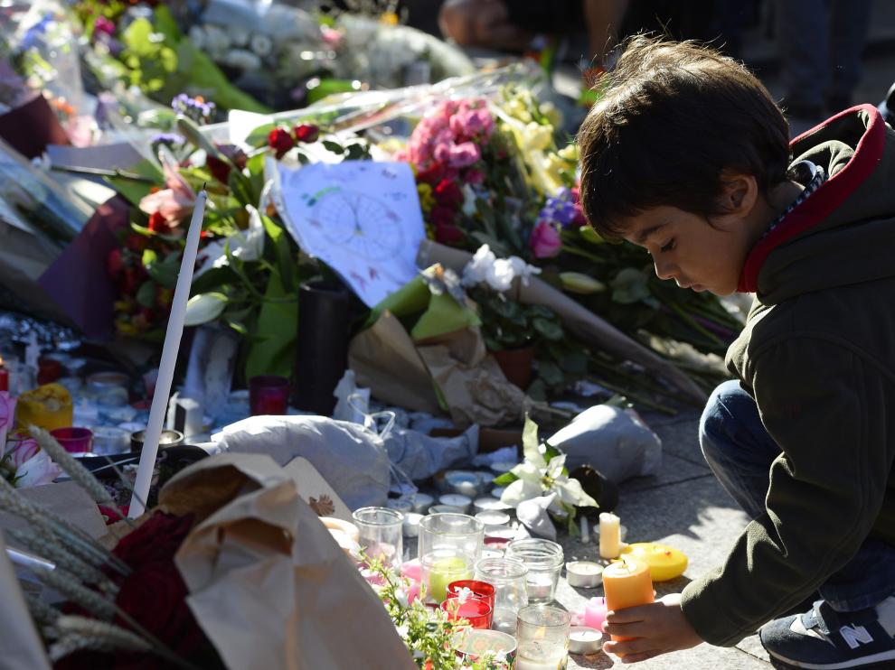 Un niño deposita un ramo de flores en uno de los lugares de los atentados