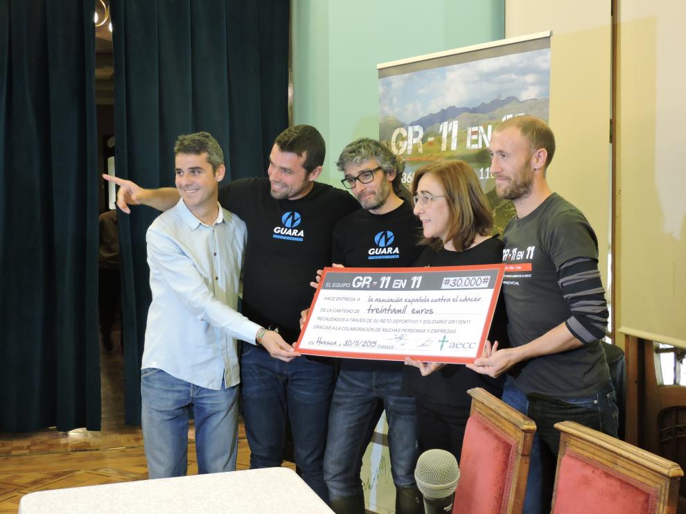Los cuatro deportistas entregando el cheque a Aurora Calvo, presidenta de la Asociación Española contra el Cáncer en Huesca.