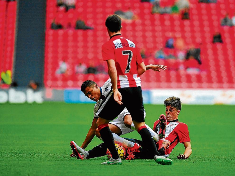 Etxeberría, en el suelo, y Guarrotxena, de espaldas, dos de los jóvenes titulares del Bilbao Athletic pugnan por el balón con Machís en la visita del Huesca a San Mamés que concluyó con empate a cero.
