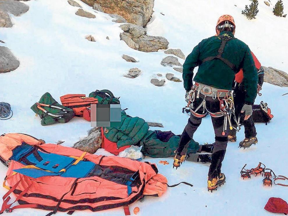 El montañero herido, tendido en el suelo, es atendido por un médico y un guardia de rescate.