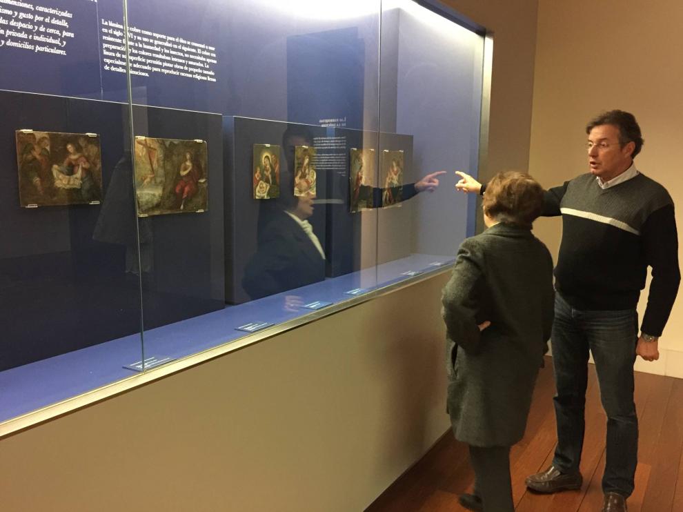 Un voluntario de los amigos del Museo enseña a una visitante los dos nuevos crismones.