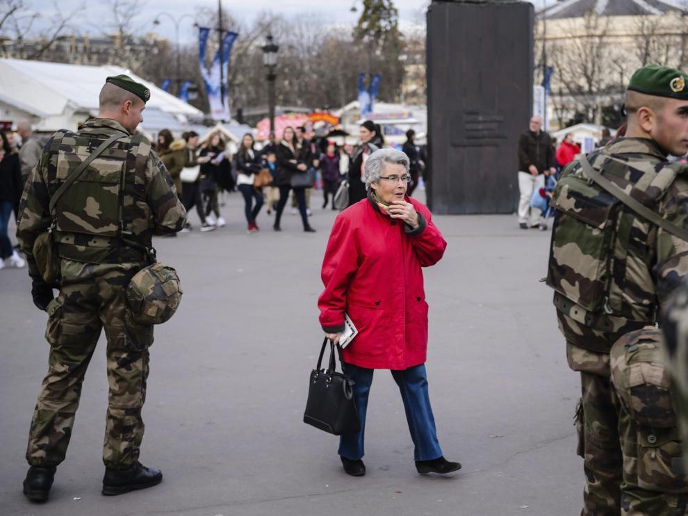 Una mujer camina junto a dos soldados franceses.