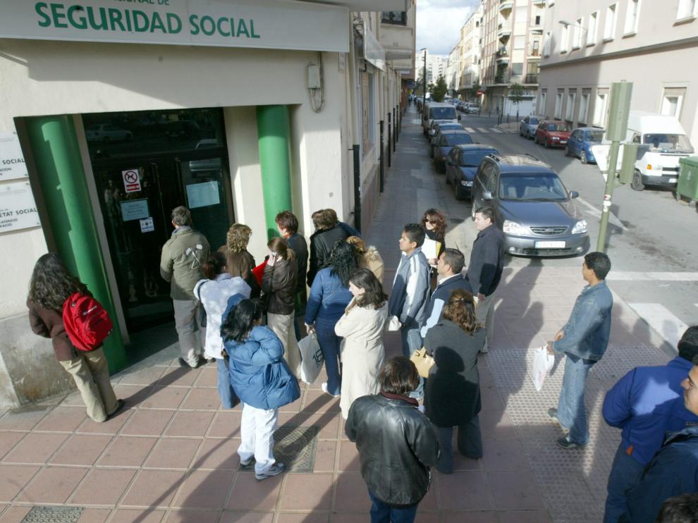 Unos ciudadanos guardan fila ante una oficina de la Seguridad Social.