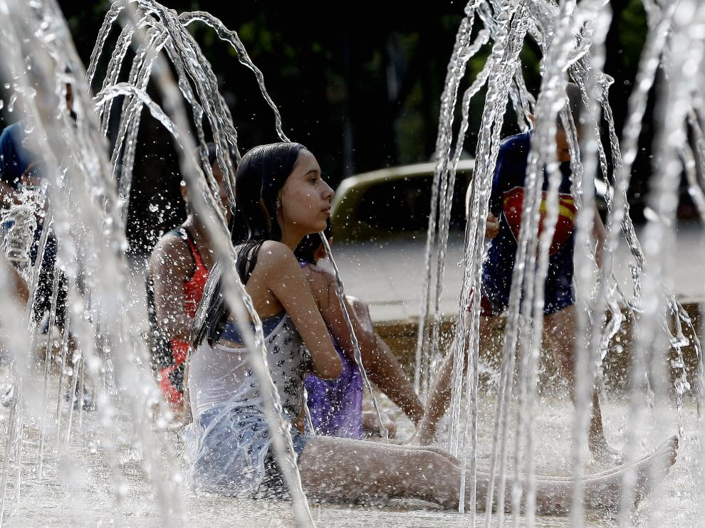Una mujer se baña con su pequeña en un parque de Medellín (Colombia), donde el Gobierno ha pedido a sus ciudadanos que cuiden su salud frente a las altas temperaturas.