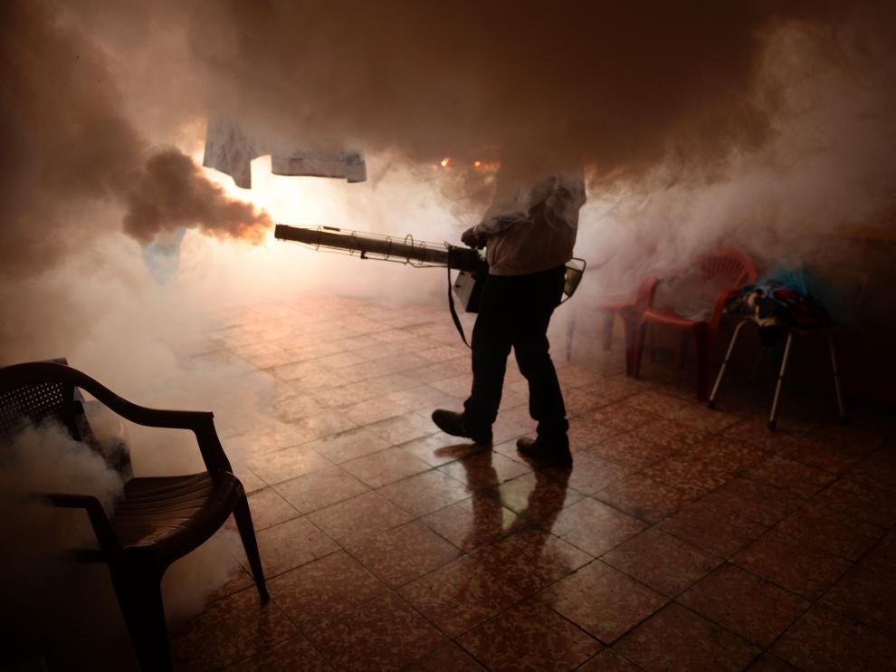 Un operario de Salud Pública fumiga un establecimiento para prevenir el virus del zika en San Salvador.