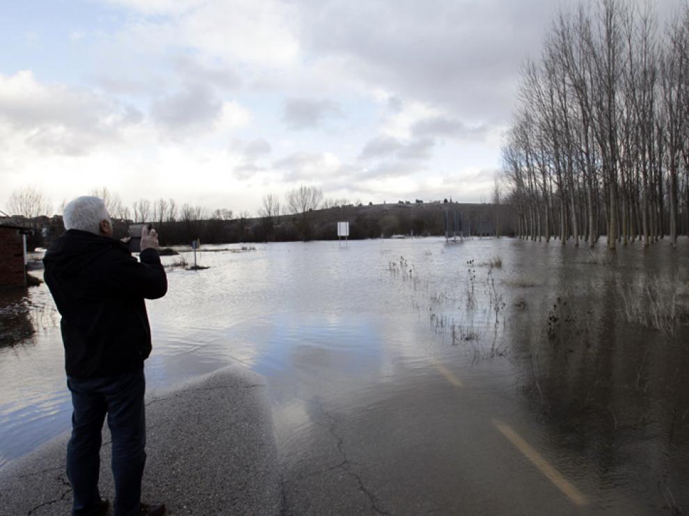 Un hombre fotografía el inusual e inundado panorama de las cercanías del río Duero en Garray.