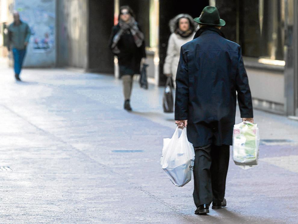 Un transeúnte pasea por Zaragoza con dos bolsas de plástico.