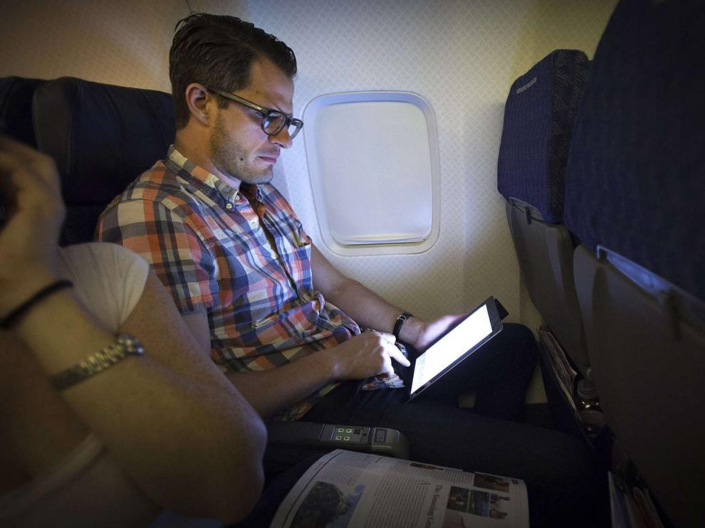 Un pasajero utilizando una tableta durante un viaje a bordo de un avión