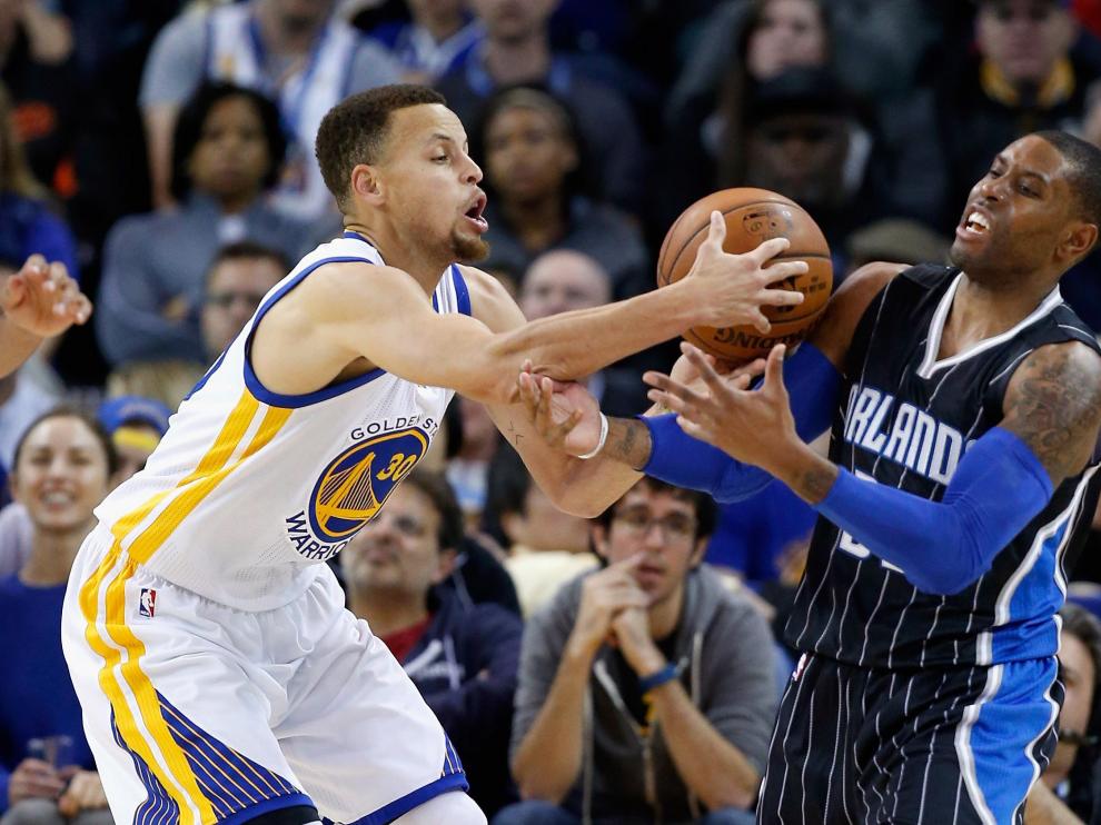 Curry sujeta el balón ante un adversario