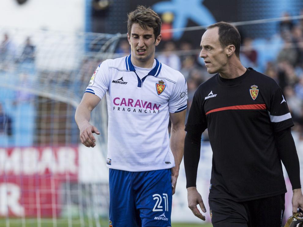 Momento en el que Joan Campins abandona el campo lesionado, acompañado del fisioterapeuta Míchel Román, en el partido ante el Girona del pasado domingo.
