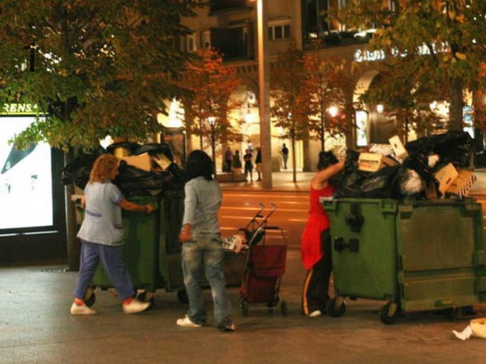 Un grupo de personas buscan comida en un contenedor| HA