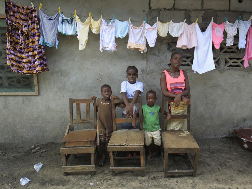 Victoria Topay (d) y sus hijos posan junto a sillas vacías que simbolizan a su marido y otros familiares fallecidos víctimas del ébola en Monrovia.