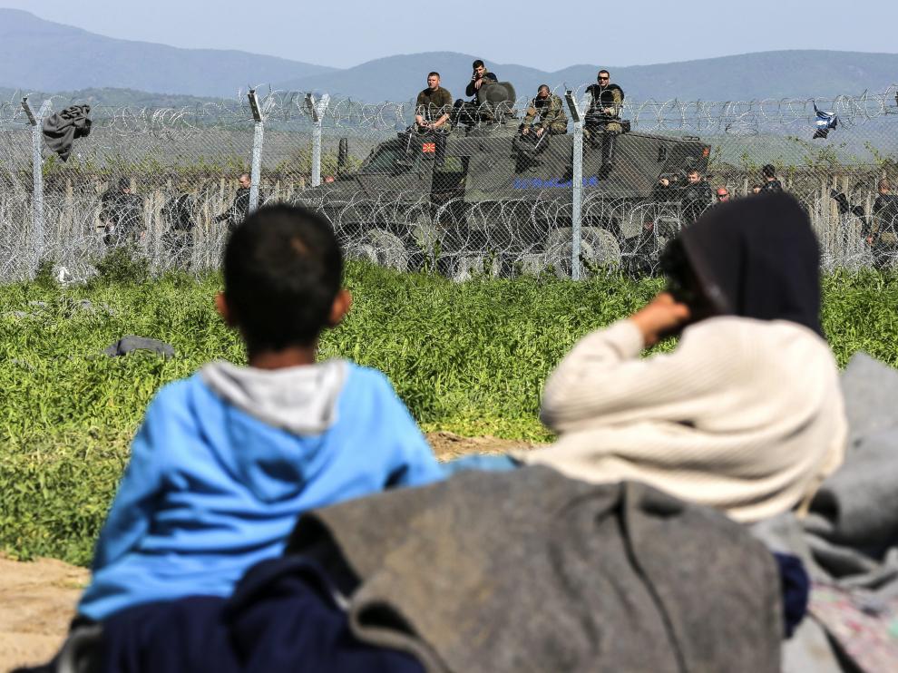 Unos niños descansan junto a la valla fronteriza en un campo de refugiados.