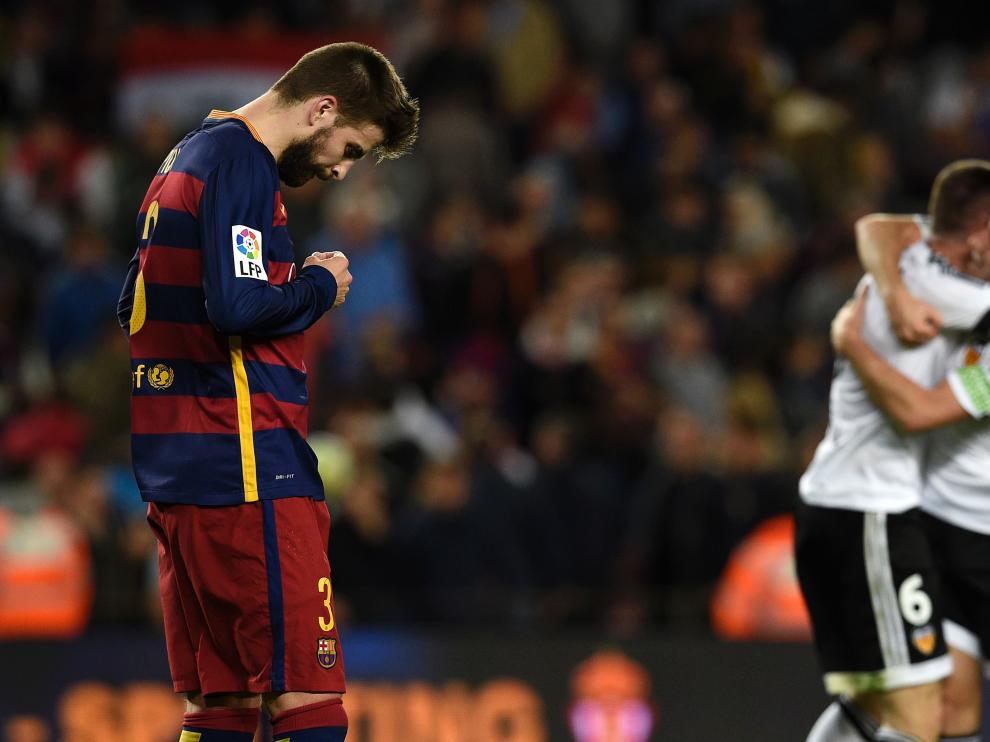 El defensa, Gerard Piqué, se lamenta mientras los jugadores del Valencia celebran la victoria.