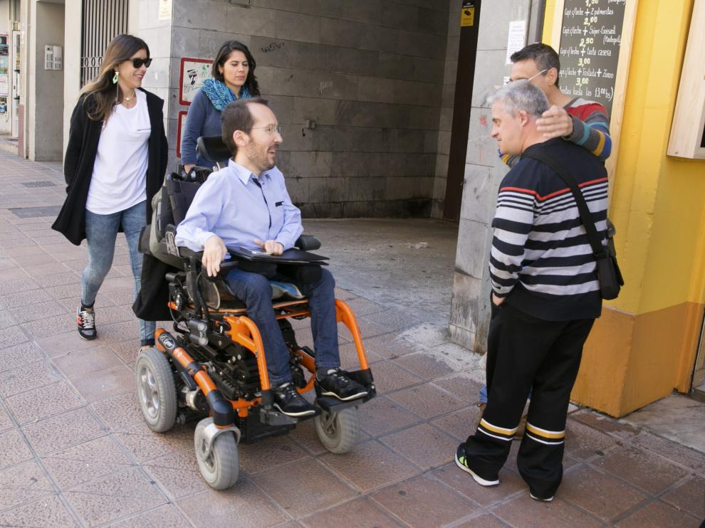 El secretario de Organización de Podemos, Pablo Echenique, saluda a unos ciudadanos en su camino hacia la rueda de prensa