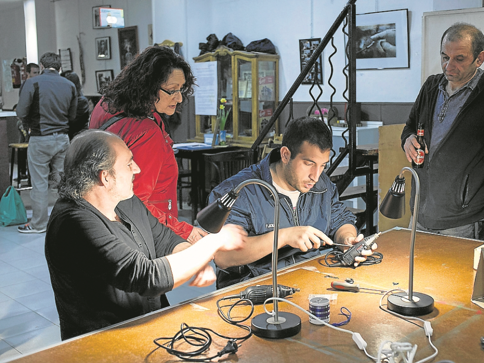 Luis Martín (centro), en pleno arreglo en el Repair Café de La Vía Láctea, en Zaragoza.