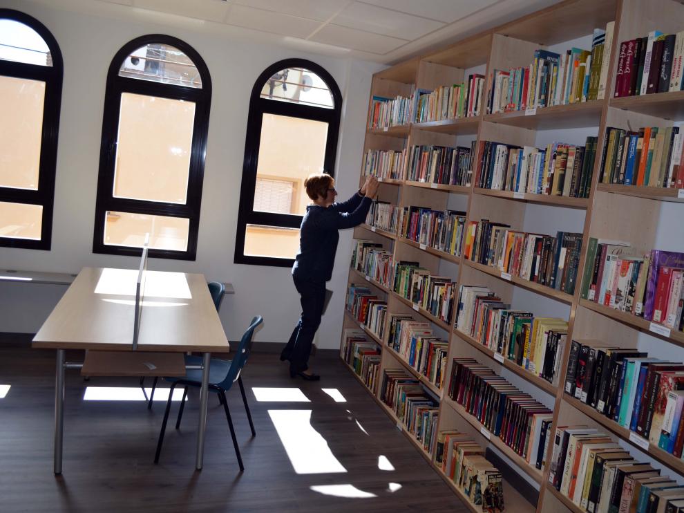 Una voluntaria coloca los libros de la nueva biblioteca.