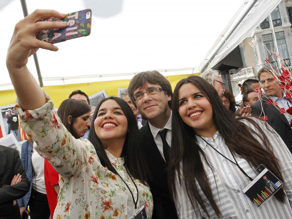 El president de la Generalitat, Carles Puigdemont, se hace una selfie con dos jóvenes en la caseta de la Asamblea Nacional Catalana