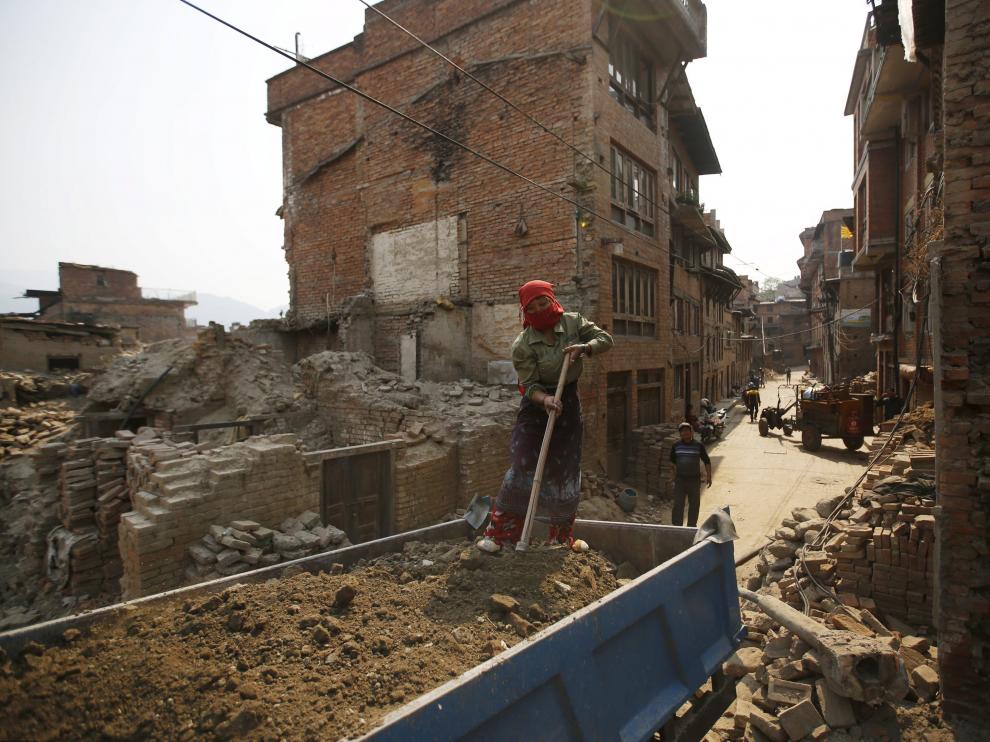 Una mujere trabaja en la reconstrucción de una vivienda en Nepal, un año después del terremoto.