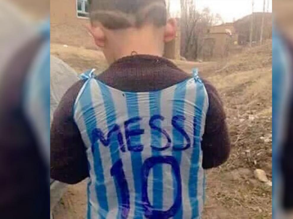 El niño afgano Murtaza muestra la camiseta de Messi de plástico.