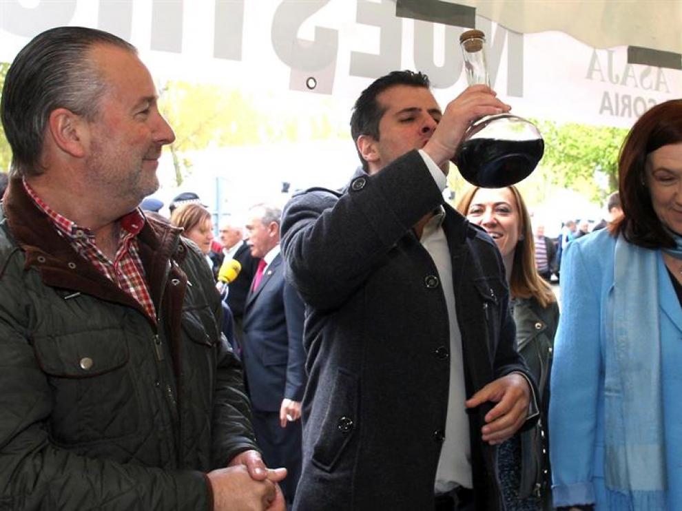 El secretario del PSOE CyL, Luis Tudanca (c), bebe de un porrón, junto al presidente de ASAJA, Donaciano Dujo (i), y la subdelegada del Gobierno, María José Heredia (d), durante la inauguración de la 56ª Feria de Muestras de Almazán