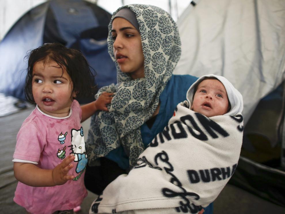 Una madre sostiene a sus dos hijos en el campo de refugiados de Idomeni.