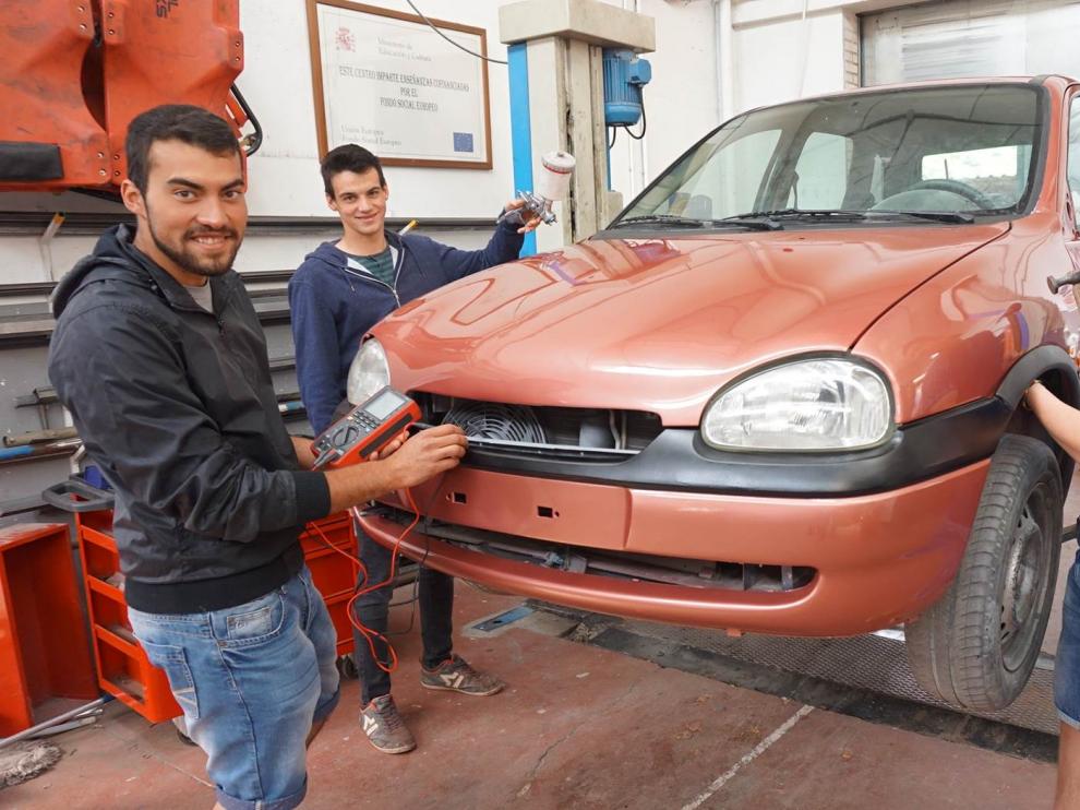 En la foto, los tres alumnos de automoción del IES Martínez Vargas arreglando un coche en el taller del centro.