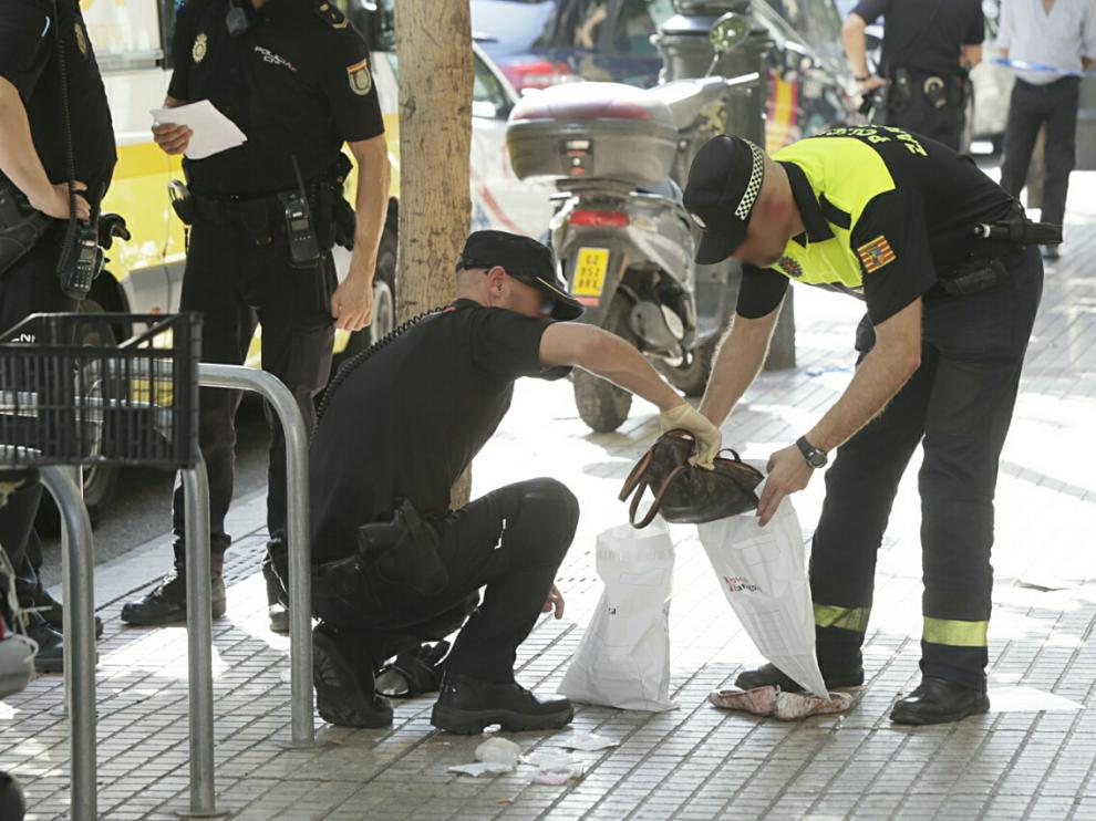Dos agentes recogen el bolso de la víctima en el lugar de los hechos
