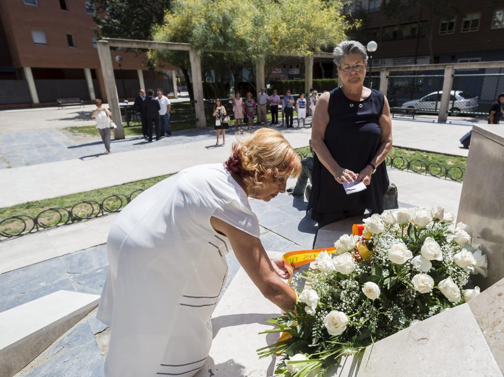 Marta Berdor, de blanco, y María Gracia Roca, colocan flores en el monumento de la casa cuartel.