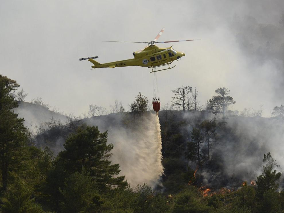 Un helicóptero suelta agua para sofocar el fuego que había llegado a los barrancos en Atarés .