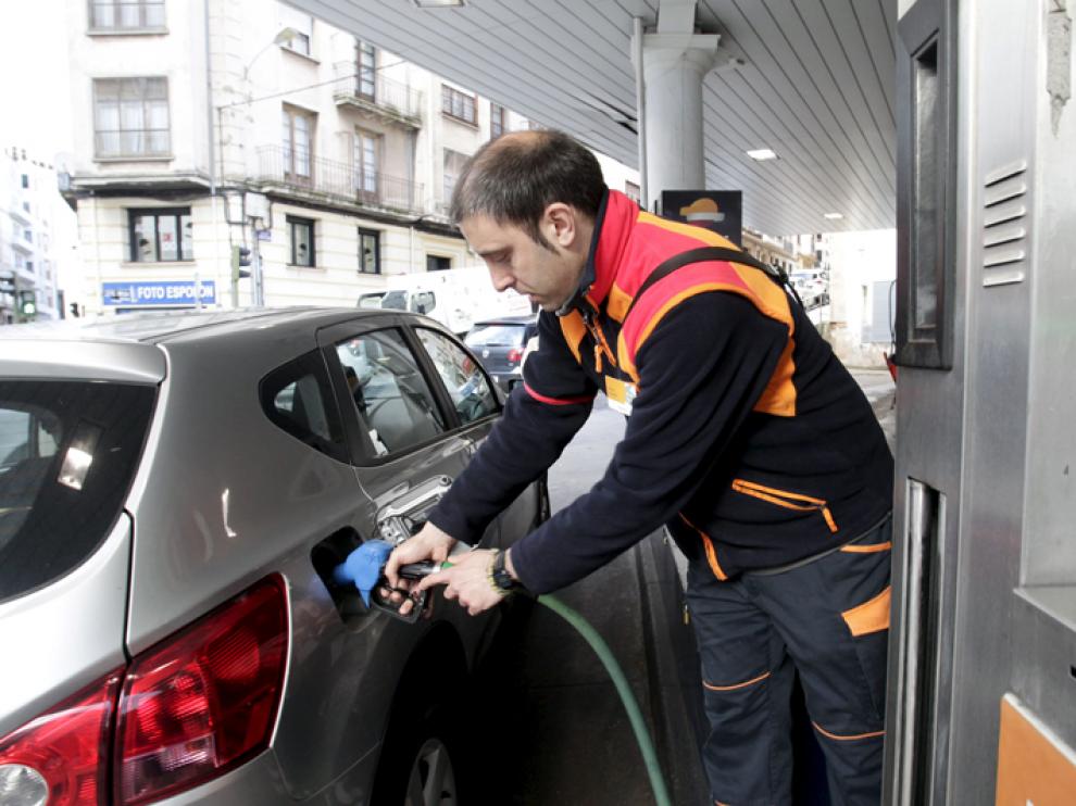 Trabajador de una gasolinera echando combustible a un turismo, imagen de archivo