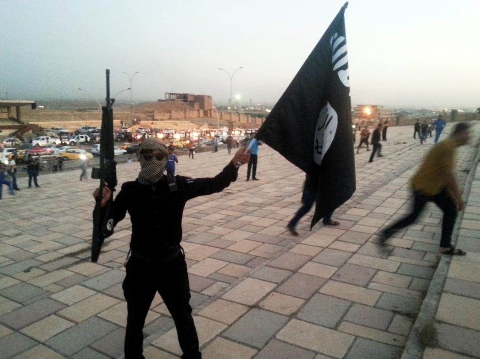 Un combatiente del Estado Islámico sostiene un arma y una bandera en la ciudad iraquí de Mosul.