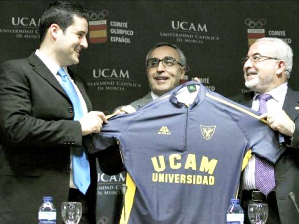 José Luis Mendoza (a la derecha), presidente de la UCAM, entrega una camiseta de su club al piragüista olímpico David Cal (izda.) en presencia de Alejandro Blanco (centro), presidente del Comité Olímpico Español.