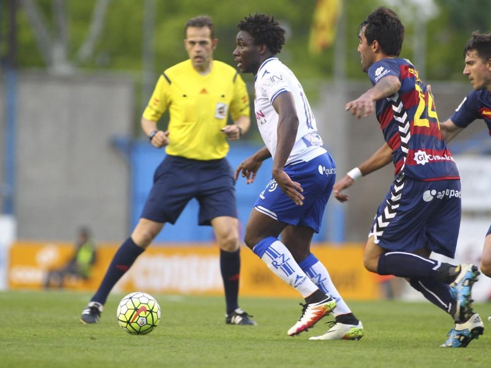 El árbitro Jorge Valdés Aller, en segundo plano, observa una jugada de Dongou ante dos rivales del Llagostera en el partido final de la pasada temporada, el 4 de junio en Palamós.