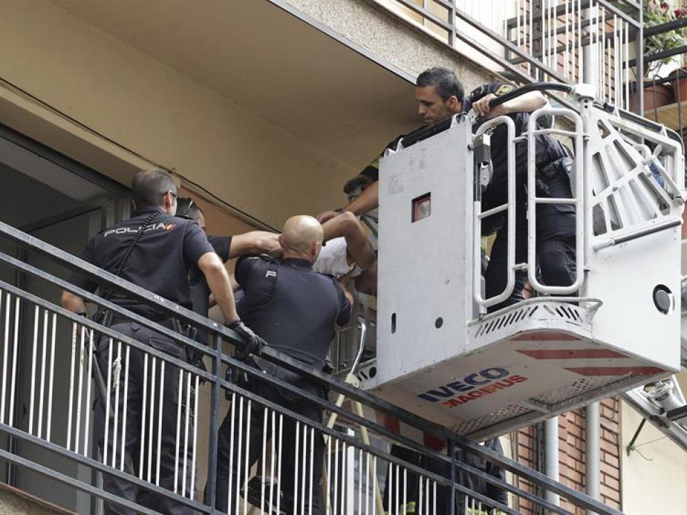 Efectivos de la Policía Nacional sacan de la vivienda por una escalera de Bomberos a uno de los jóvenes que han sido detenidos en Salamanca