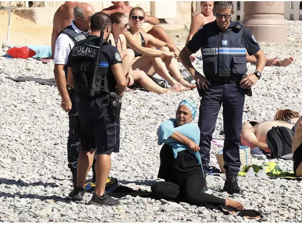 La policía obliga a una mujer a quitarse el burkini en una playa de Niza.