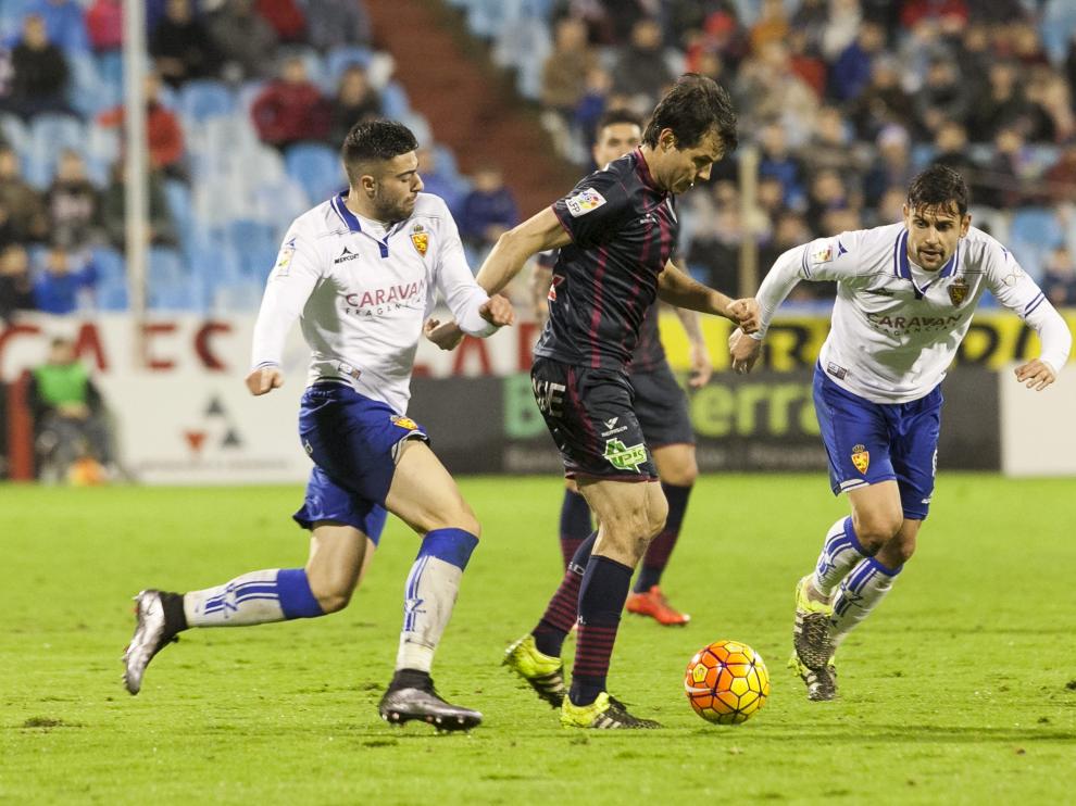 Juanjo Camacho avanza entre Diego Rico y Albert Dorca en el derbi del pasado curso en La Romareda.