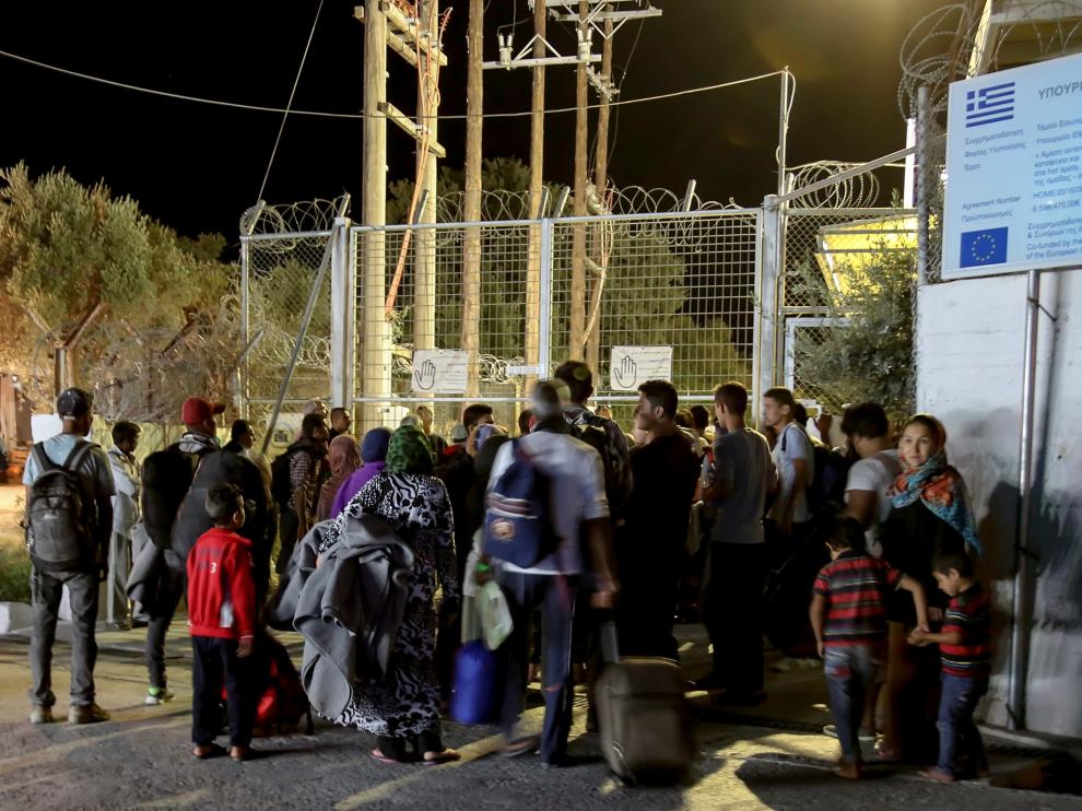 Refugiados y migrantes permanecen delante de la puerta del campo de migrantes de Moria después de declararse un incendio.