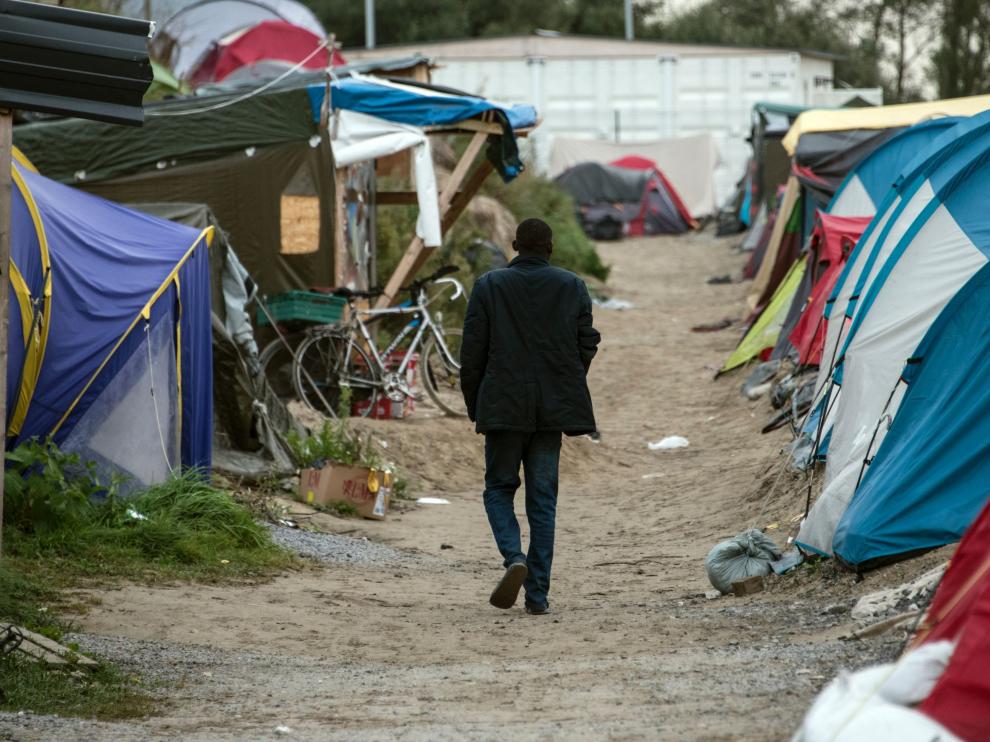 Un migrante camina en por el campamento de Calais, al norte de Francia