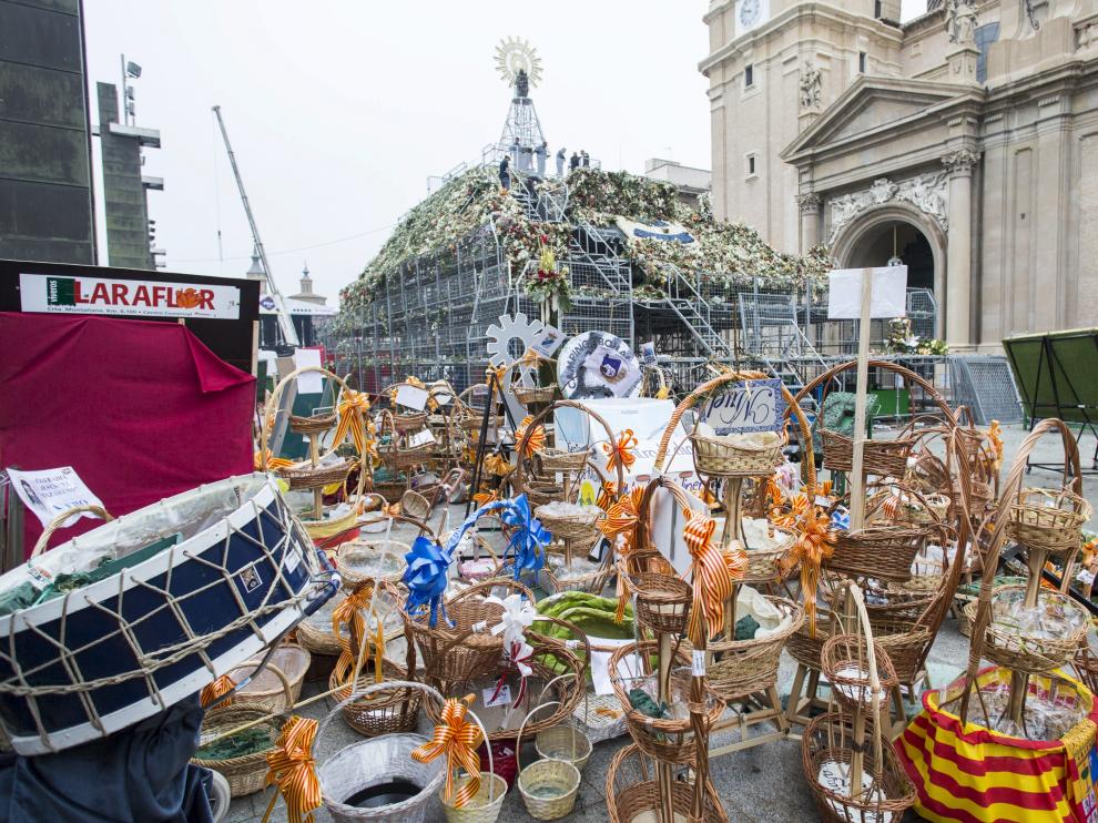 Restos de centros florales de empresas y colectivos en el manto de la Virgen.