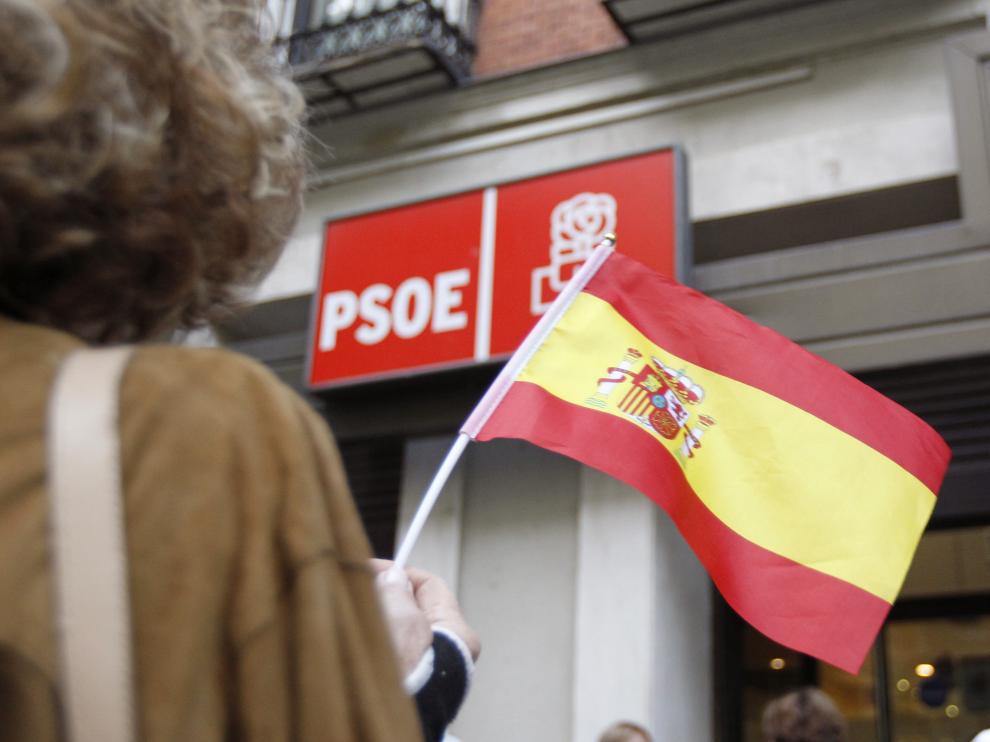 Una mujer hondea la bandera de España frente a la sede del PSOE en Madrid
