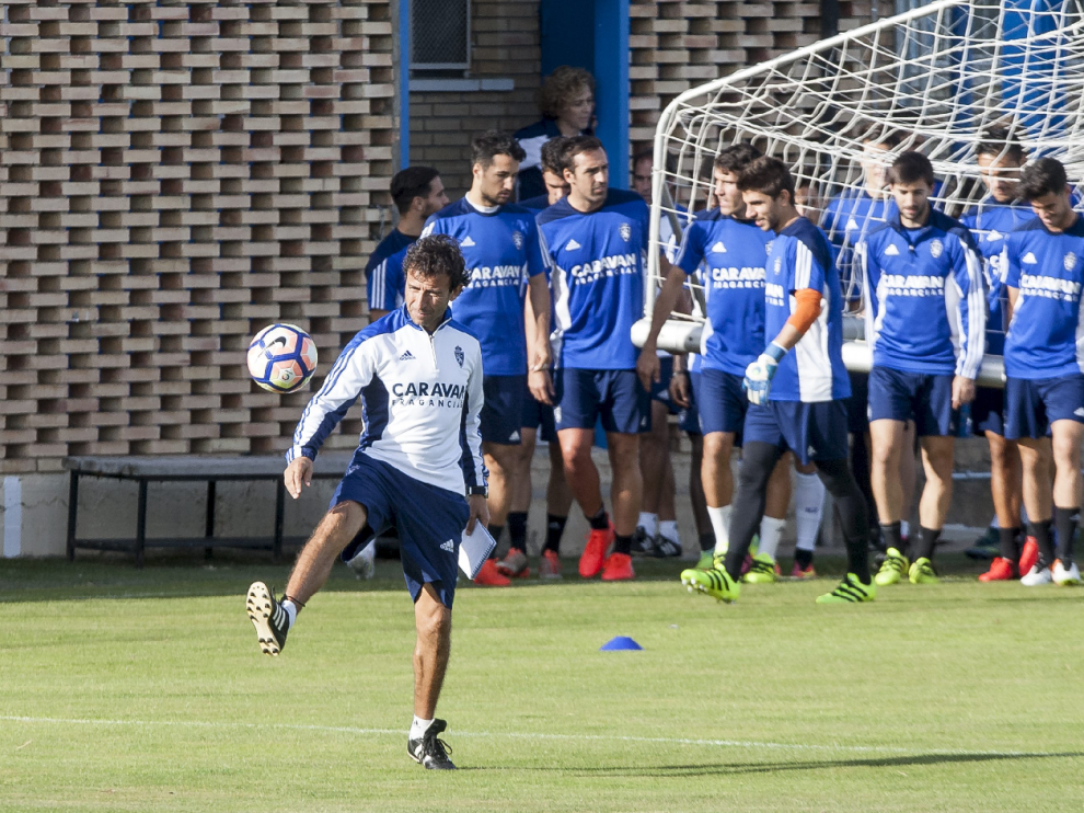 Luis Milla juega con un balón mientras los jugadores trasladan una portería móvil durante el entrenamiento.