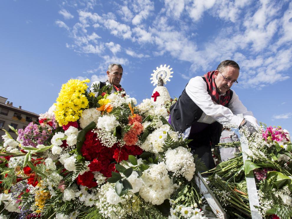 Los jardineros municipales colocan las flores en el manto de la Virgen.